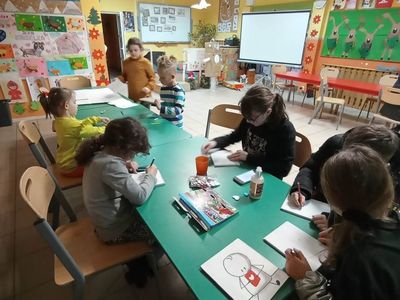 Wychowankowie z PWD z Lasek wykonują upominki mazakami i farbami na deseczce dla najbliższych.