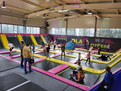 Dzieci skaczą na trampolinach.