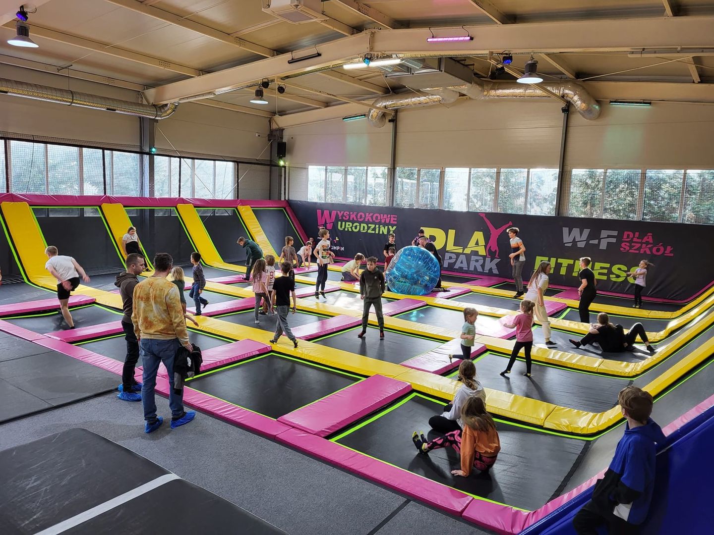 Dzieci skaczą na trampolinach.