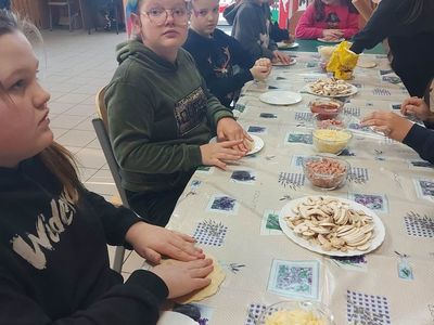 Wychowankowie z PWD z Lasek formują i dodają składniki na pizzę.