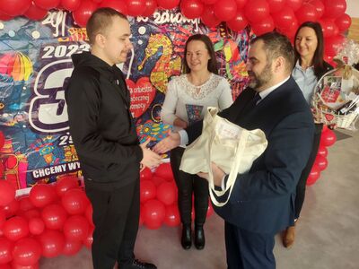 Wójt Radosław Nowakowski przekazuje gratulacje Arturowi Beśce, obok wolontariuszka Beata Hetmańska i szefowa Sztabu WOŚP Gminy Malechowo -  Eliza Wróblewska-Hencel.