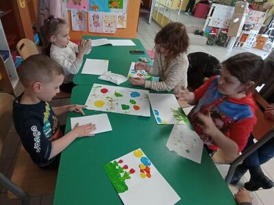 Dzieci z PWD z Lasek malują wiosenne obrazy paluszkami i farbami.