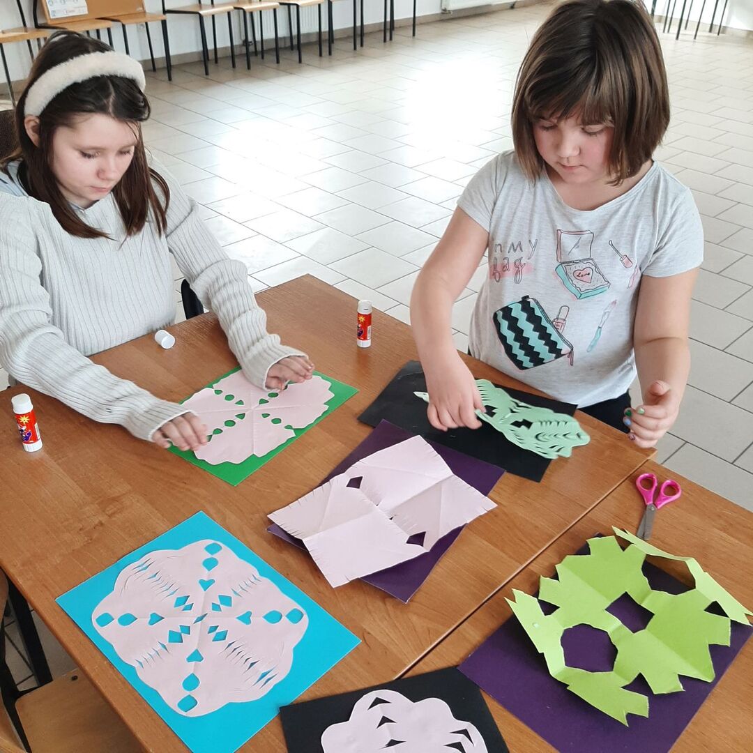Dziewczynki wycinają serwetki z papieru.