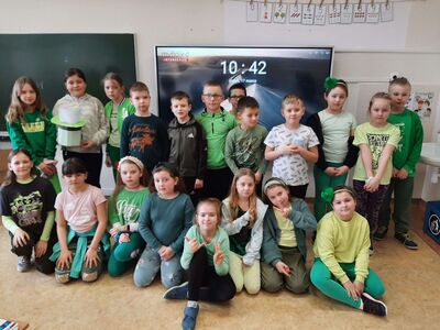 Uczniowie klas młodszych pozują do zdjęcia ubrani na zielono.