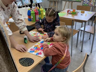 Dziewczynki malują farbami pod folią. 