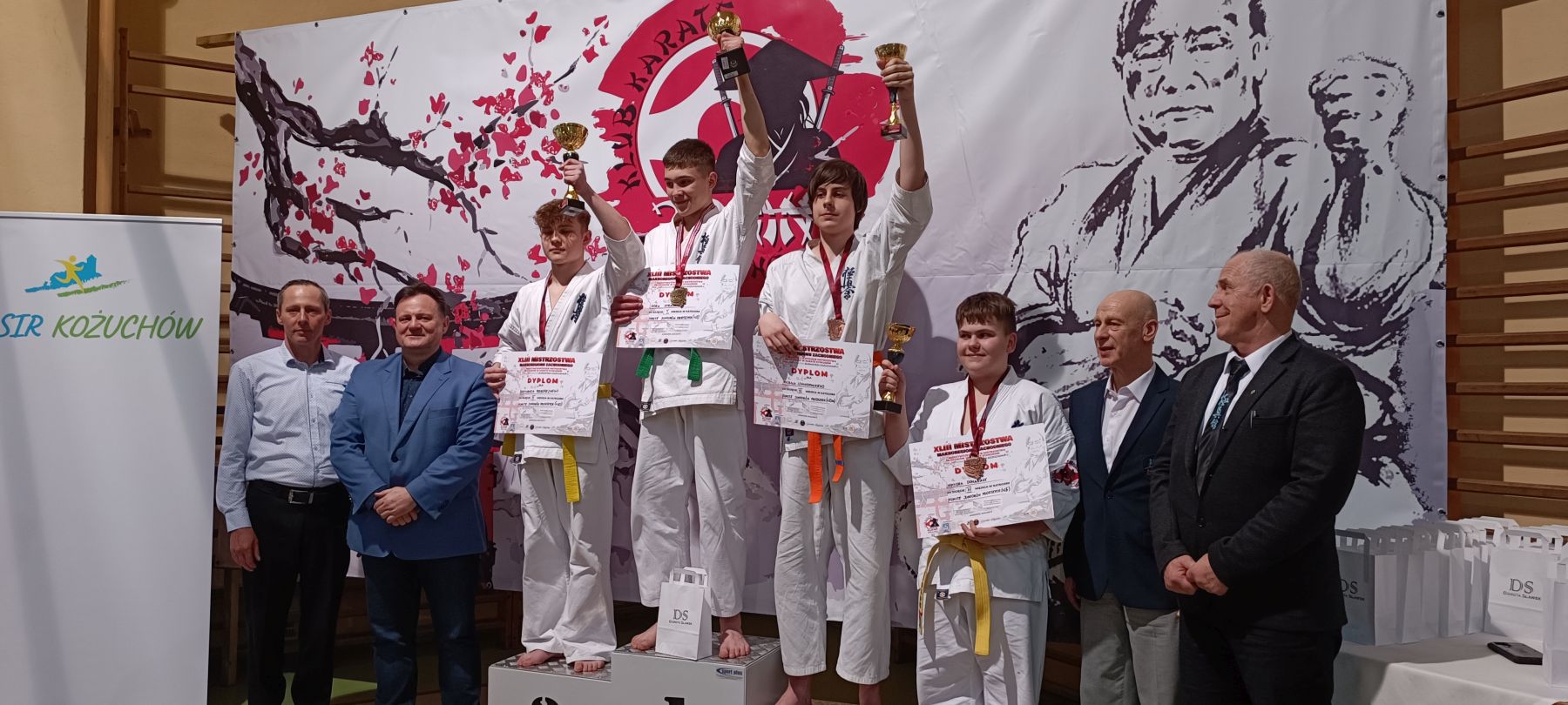 Bartłomiej Podbereżny na podium prezentuje puchar.