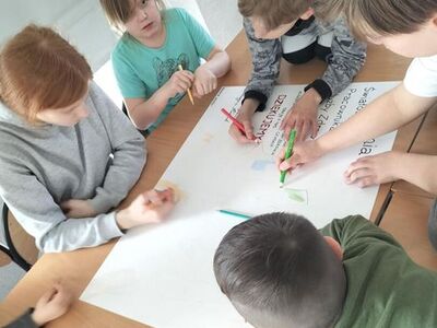 Zdjęcie przedstawia dzieci podczas pracy przy plakacie dla pracowników służby zdrowia.