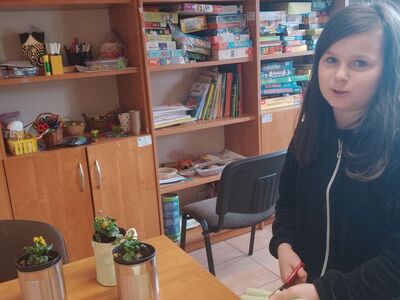 Dziewczynka wycina z bibuły osłonkę na doniczkę.