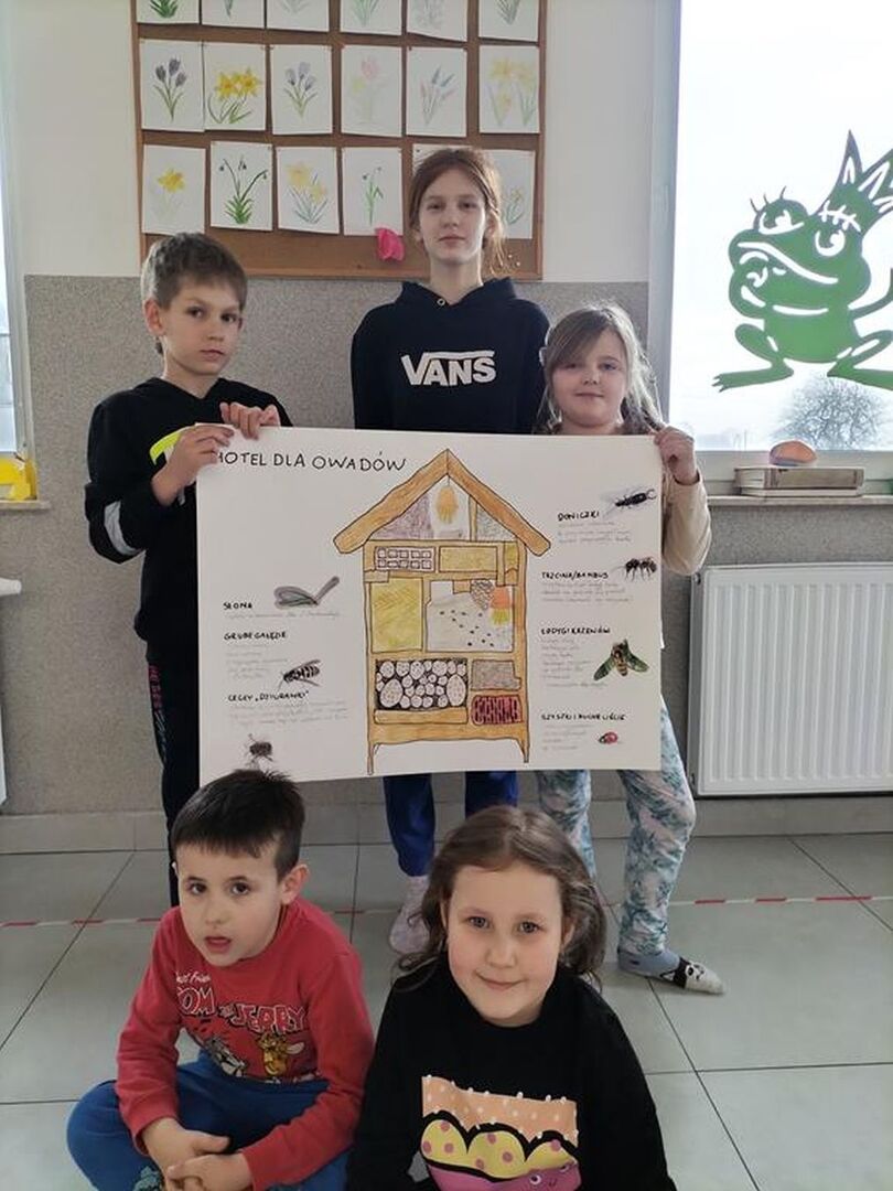 Dzieci prezentują narysowany hotel dla owadów.