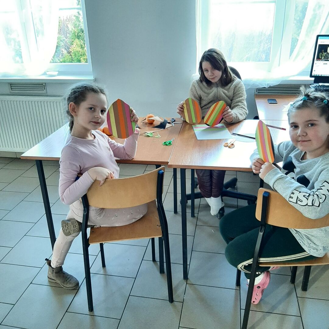 Dziewczynki prezentują wykonane pisanki z papieru.