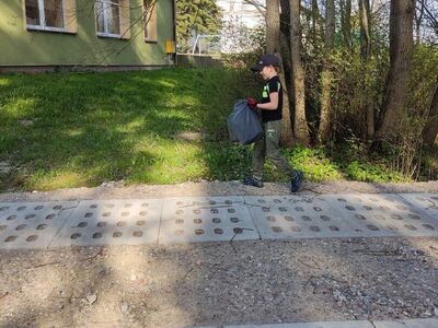 Chłopiec porządkuje teren przy świetlicy.