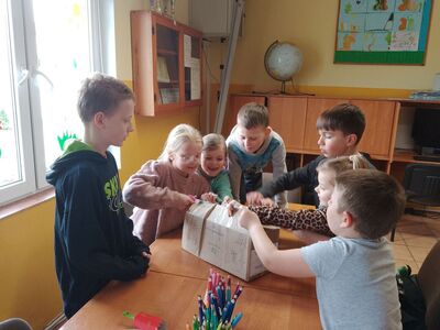 Dzieci wspólnie otwierają paczkę z nasionami.