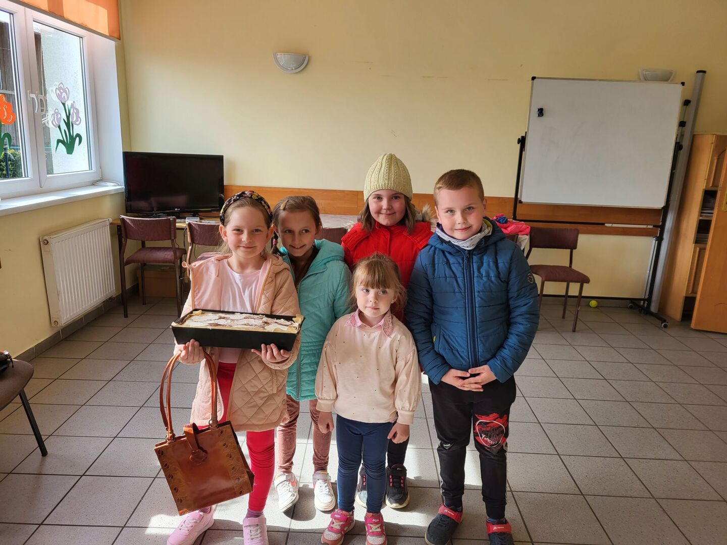 Dzieci pozują do zdjęcia z przygotowanym ciastem.