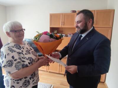 Wójt przekazuje Jubilatce bukiet kwiatów oraz list gratulacyjny.