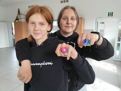 Wychowankowie prezentują wykonane pierścionki z papieru.