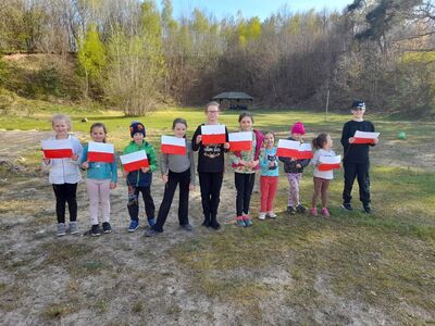 Dzieci pozują do zdjęcia z papierowymi flagami.
