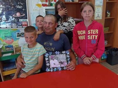 Dzieci wraz z tatą pozują do zdjęcia.