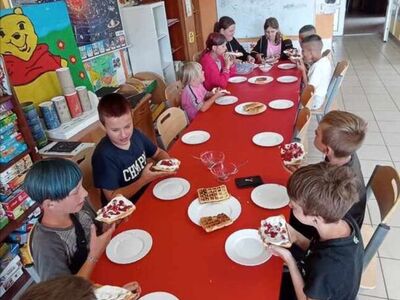 Dzieci z PWD Laski podczas degustacji gofrów z bita śmietaną i owocami.