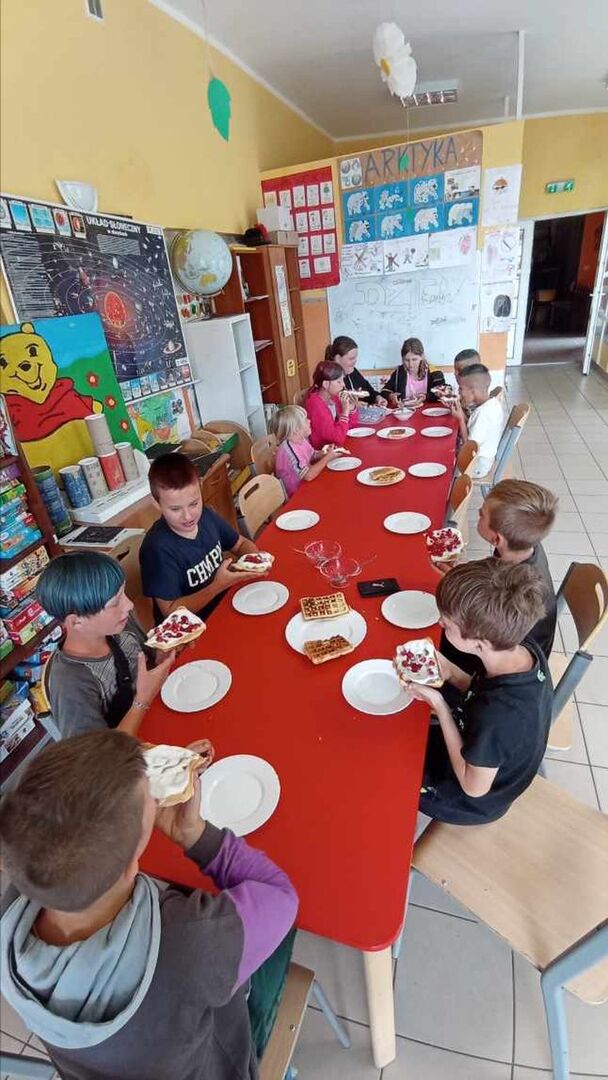 Dzieci z PWD Laski podczas degustacji gofrów z bita śmietaną i owocami.