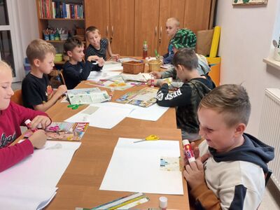 Dzieci wykonują kolaże z gazet przy użyciu pomocy dydaktycznych.
