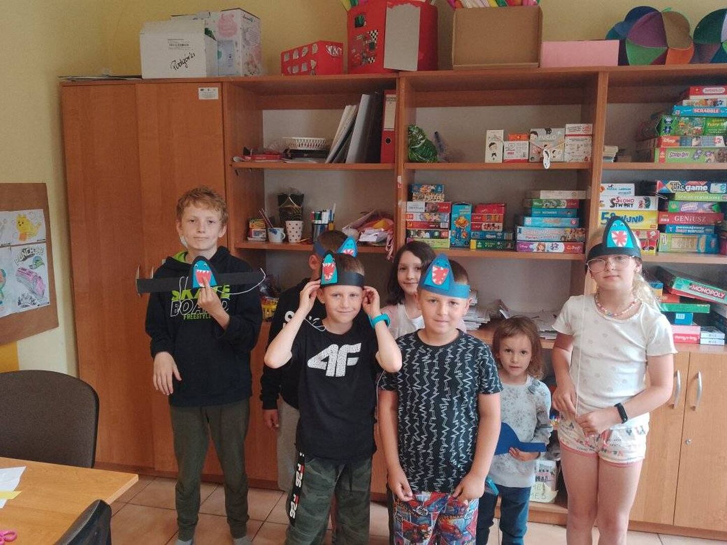 Dzieci pozują do zdjęcia z własnoręcznie wykonanymi opaskami na głowie.
