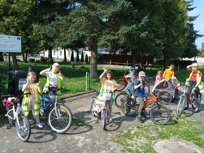 Dzieci w kamizelkach odblaskowych z rowerami.
