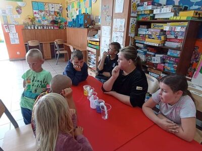 Wychowankowie z PWD z Lasek wykonują doświadczenie "Wędrująca woda".