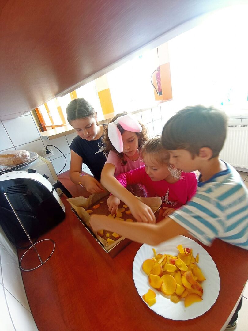 Wychowankowie z PWD z Lasek dekorują ciasto brzoskwiniami.