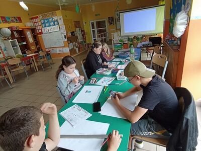 Wychowankowie z PWD z Lasek wykonują plakaty o cyberprzemocy.