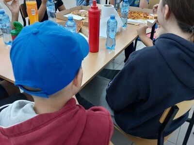 Dzieci degustują pizzę.