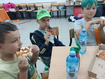 Chłopcy degustują pizzę.