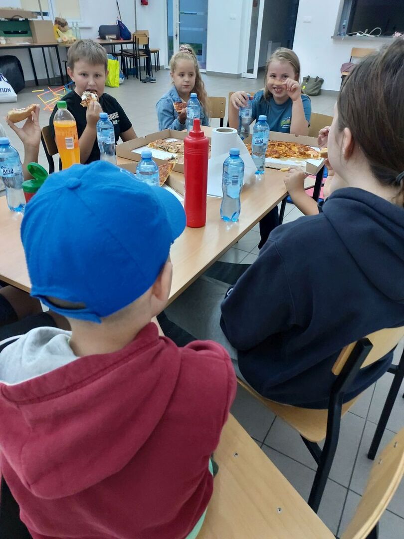 Dzieci degustują pizzę.