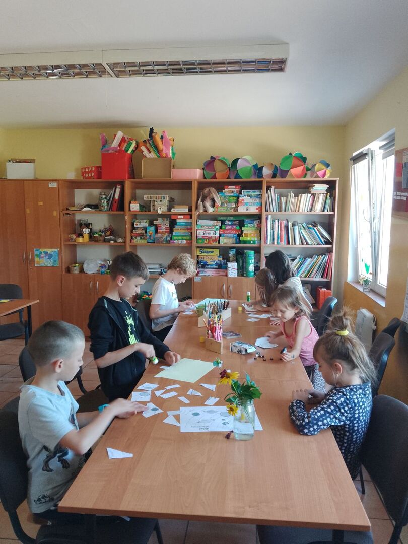 Dzieci wykonują prace plastyczne z papieru.