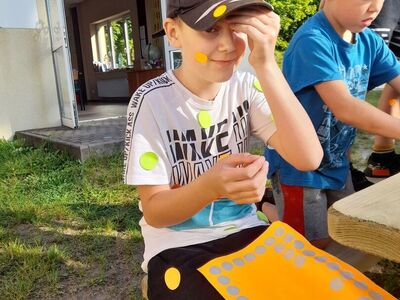 Chłopcy ozdabiają ubranie papierowymi kropkami.