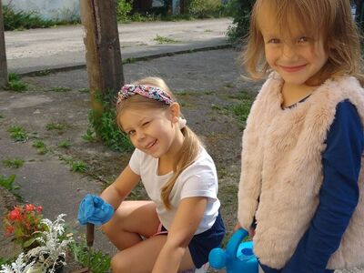 Dziewczynki pozują do zdjęcia podczas sadzenia kwiatów do skrzynki.