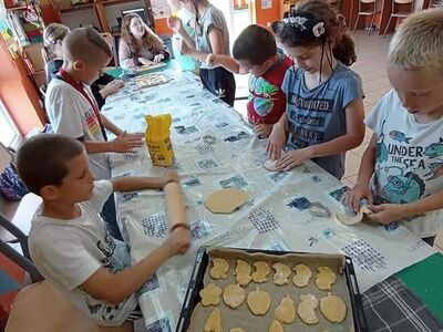 Wychowankowie z PWD z Lasek wałkują ciasto na ciasteczka.