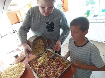 Wychowankowie z PWD z Lasek robią zapiekankę makaronową z kiełbasą, warzywami i serem.