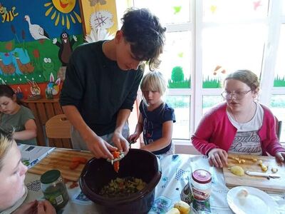 Wychowankowie z PWD z Lasek kroją warzywa na sałatkę jarzynową.