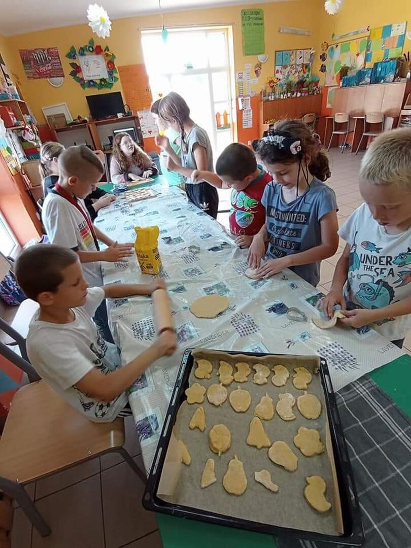 Wychowankowie z PWD z Lasek wałkują ciasto na ciasteczka.