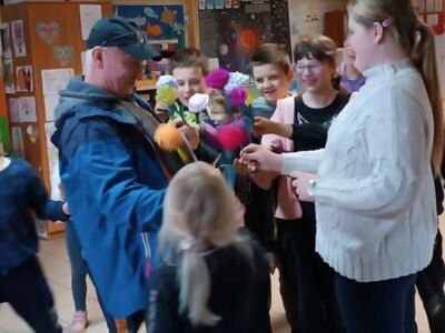 Wychowankowie z PWD z Lasek wręczają wykonane prezenty listonoszowi.