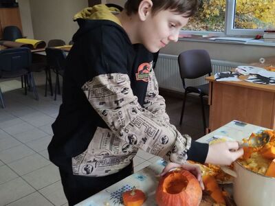 Chłopiec wycina wzorki w dyni.