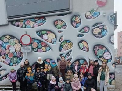 Dzieci z Placówek Wsparcia Dziennego pozują do zdjęcia na tle pracowni słodyczy.