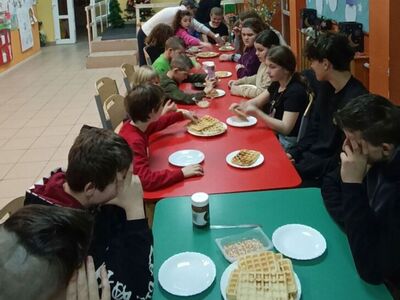 Dzieci degustują gofry z bitą śmietaną i czekoladą.