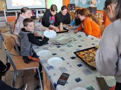Dzieci degustują pizzę.
