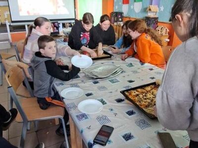 Dzieci degustują pizzę.