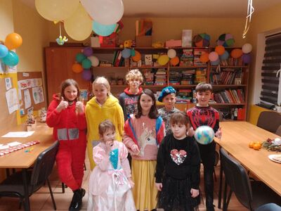 Dzieci pozują do zdjęcia w strojach karnawałowych.