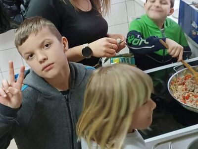 Dzieci wraz z wychowawcą smażą składniki do spaghetti.