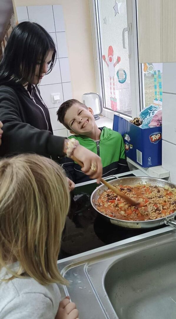 Wychowankowie z pomocą wychowawcy przygotowują sos.