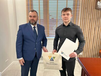 Nagrodzony sportowiec Bartłomiej Podbereżny z dyplomem i nagrodą przyjmuje gratulacje od wójta Radosława Nowakowskiego. 