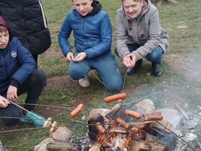 Dzieci podczas rozpalania ogniska i smażenia kiełbas.